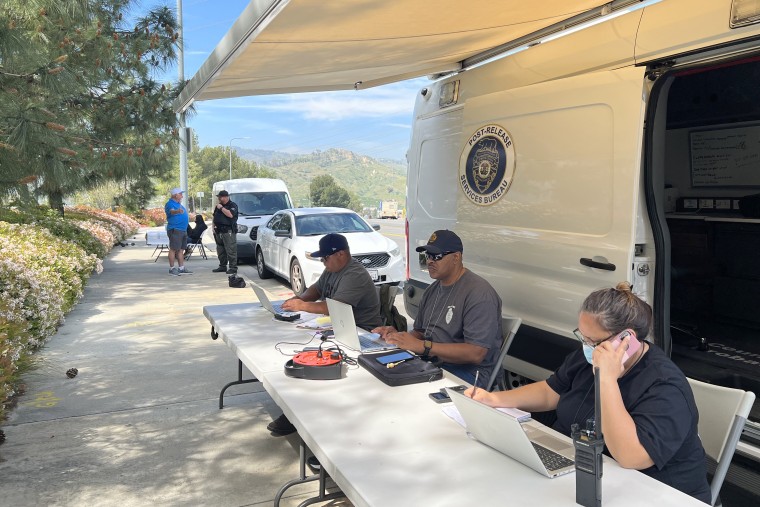 Probation officers waiting to meet with former inmates, who recently left prison, in front of a Los Angeles County Probation Department’s mobile resource center van site in Sylmar, Calif. 