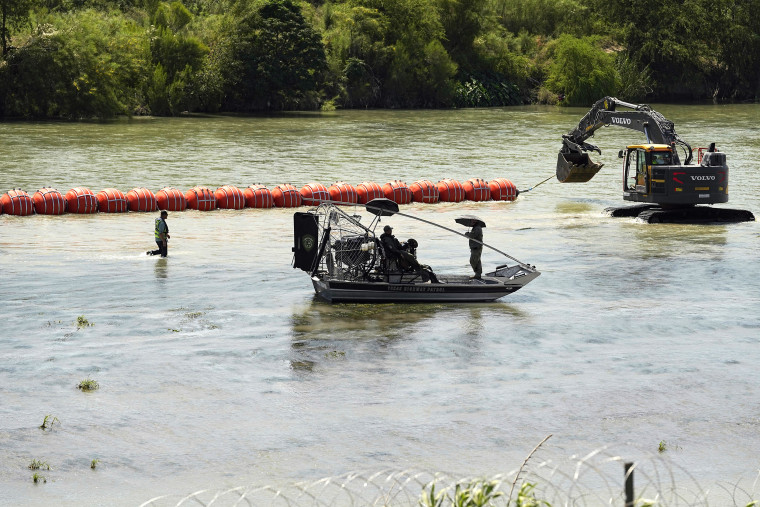 Texas State Troopers watch from an airboat as workers deploy a string of large buoys to be used as a border barrier at the center of the Rio Grande near Eagle Pass, Texas, Tuesday, July 11, 2023. The floating barrier is being deployed in an effort to block migrants from entering Texas from Mexico. (AP Photo/Eric Gay)