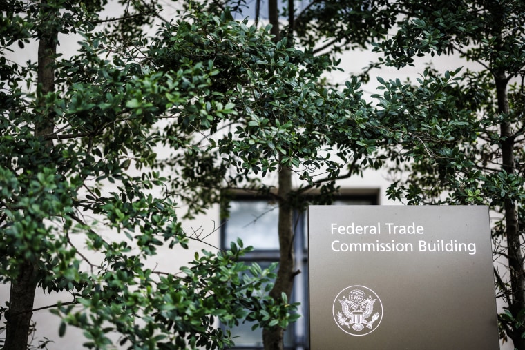The Federal Trade Commission headquarters sign in the midst of tree branches and leaves