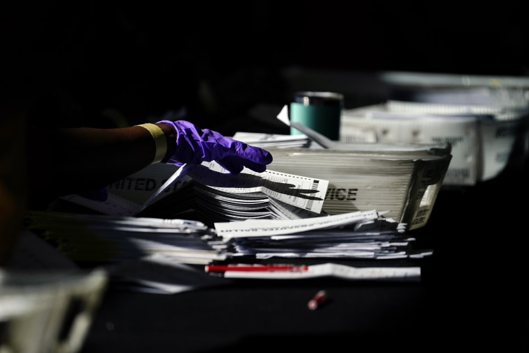 A hand works with ballots while counting votes