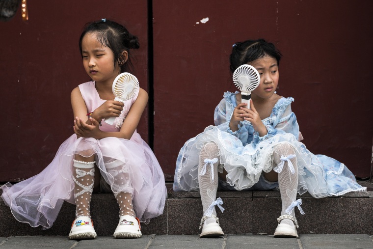 Image: Children cool themselves with electric fans as they take a rest near the Forbidden City on a hot day in Beijing, June 25, 2023.