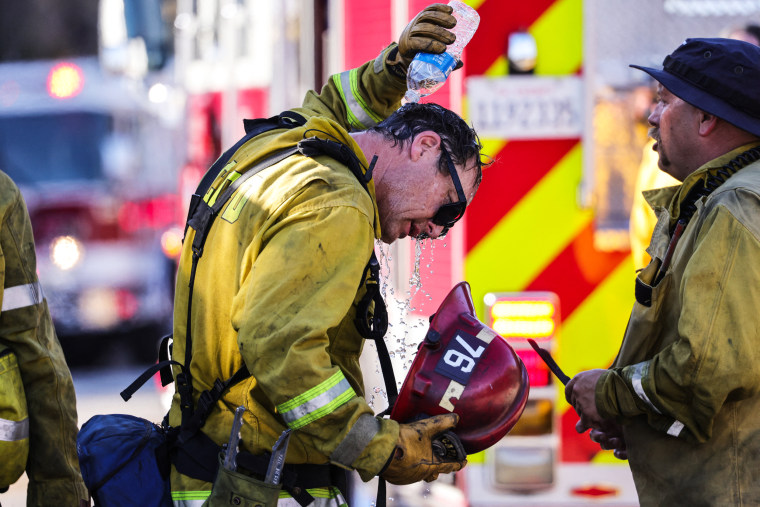 Image: A San Bernardino County firefighter pours water over his head as the Oak Fire burns near Fontana, Calif., on Juy 19, 2023.