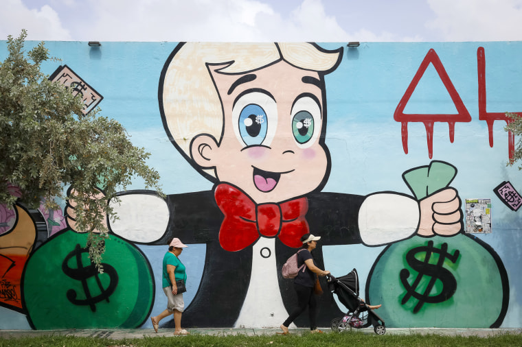 People walk pass a giant mural made by Alec Monopoly on July 20, 2023 in Wynwood, Miami’s art district, Florida.