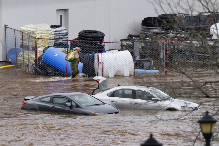 A man walks past cars abandoned in floodwaters in Halifax, Nova Scotia, Canada