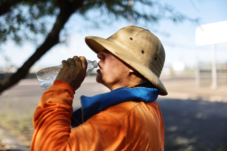 PHOENIX, ARIZONA - JULY 24: Yolanda Magana drinks water while taking a break from her work trimming trees ahead of monsoon season on July 24, 2023 in Phoenix, Arizona. While Phoenix endures periods of extreme heat every year, today is predicted to mark the 25th straight day of temperatures reaching 110 degrees or higher, a new record amid a long-duration heat wave in the Southwest. Scientists say it is likely that July will go down as the hottest month worldwide on record. (Photo by Mario Tama/Getty Images)