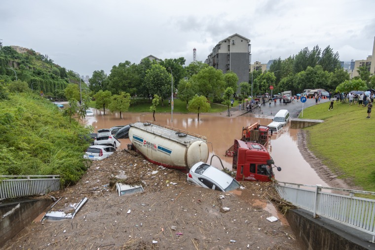 Vehicles parked on the side of a road are stuck in flood waters in Chongqing, China