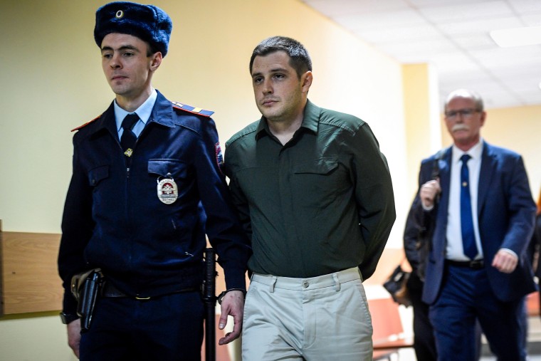 Police officers escort U.S. ex-marine Trevor Reed, charged with attacking police, into a courtroom prior to a hearing in Moscow on March 11, 2020.