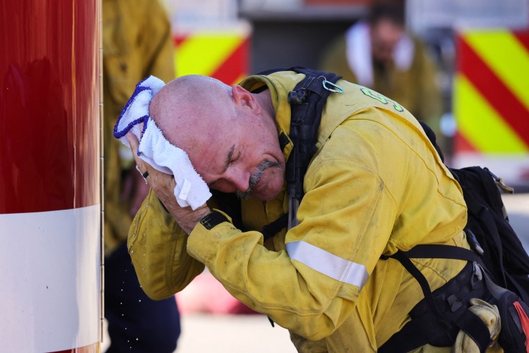 A San Bernardino County firefighter wipes his head as the Oak Fire burns near Fontana, Calif.