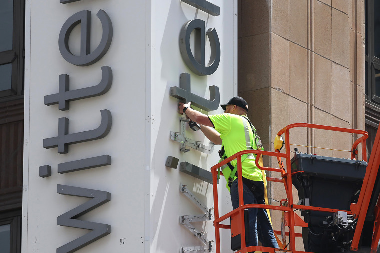A worker removes letters from the Twitter sign on the exterior of Twitter headquarters in San Francisco