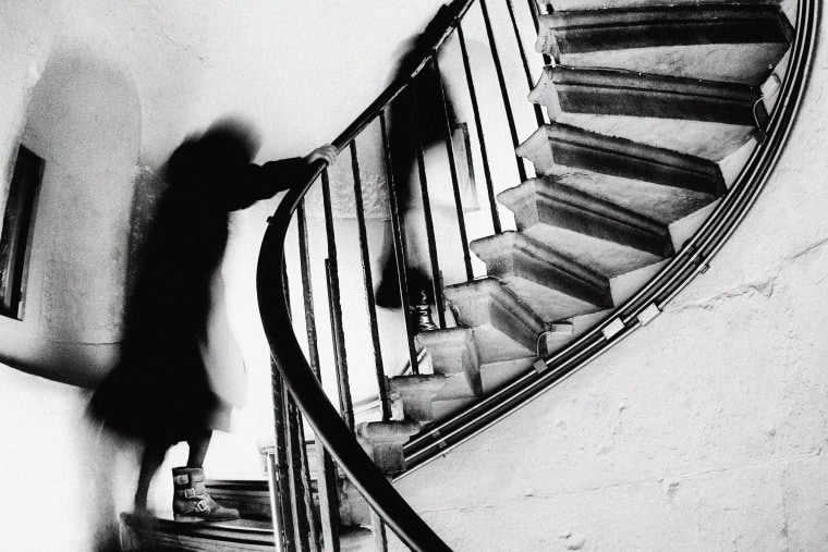 A motion blurred woman climbing a spiral staircase