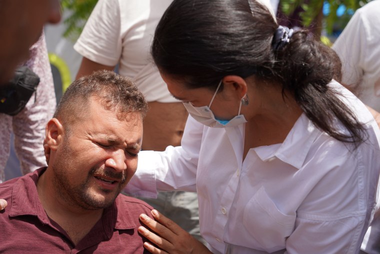 Gladys Cañas, a migrant advocate, comforts Enrique Blanco, 34, who was loaded onto an ambulance after complaining of severe leg pains while staying at a tent camp in Matamoros, Mexico.