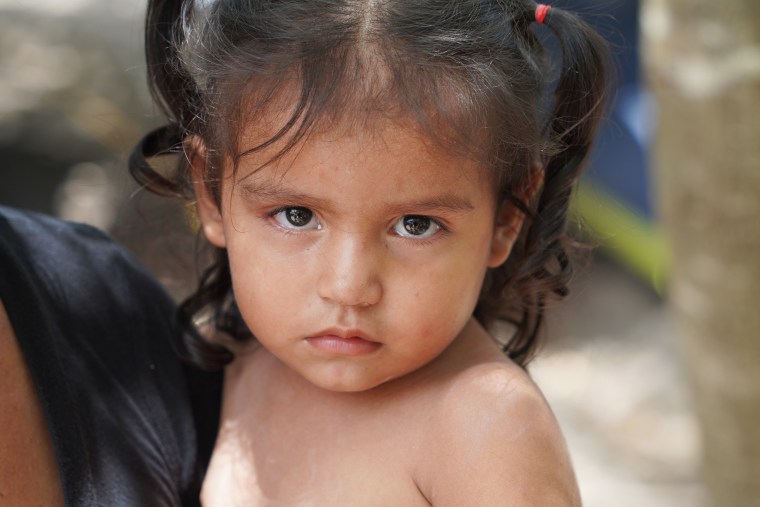 A grandmother holds her 2-year-old in Matamoros, Mexico, as her family waits for an appointment to present themselves at the Brownsville, Texas, port of entry.