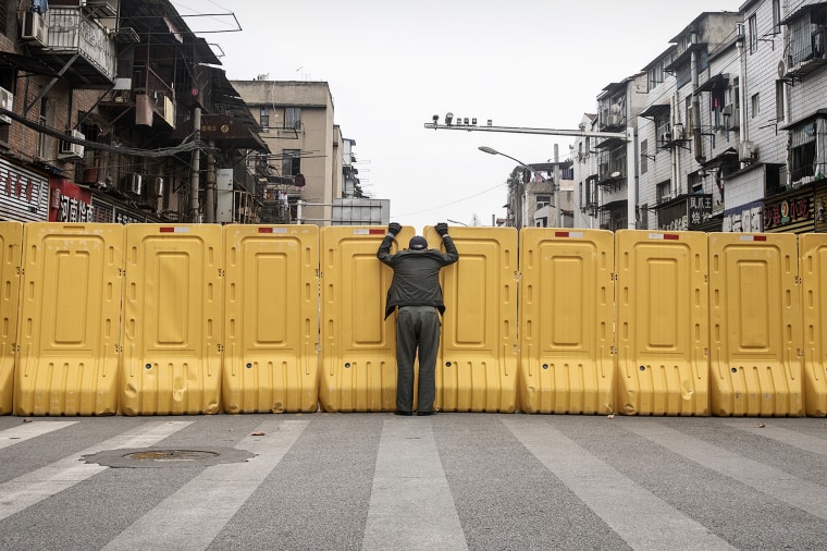 A man talks to another person through a makeshift barricade to control entry and exit to a residential compound on March 8, 2020 in Wuhan, China.
