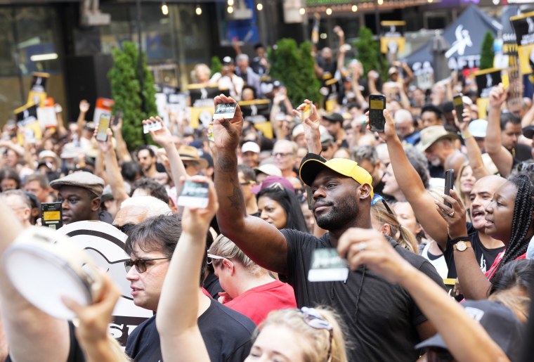 Actors hold up their SAG-AFTRA membership cards during the "Rock the City for a Fair Contract" rally in Times Square on Tuesday, July 25, 2023, in New York. The actors strike comes more than two months after screenwriters began striking in their bid to get better pay and working conditions.