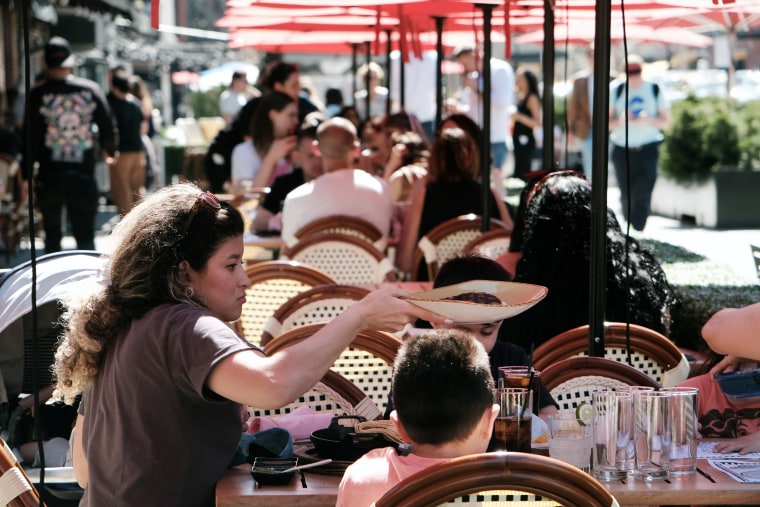 People eat at an outdoor restaurant in New York City in April 2023.