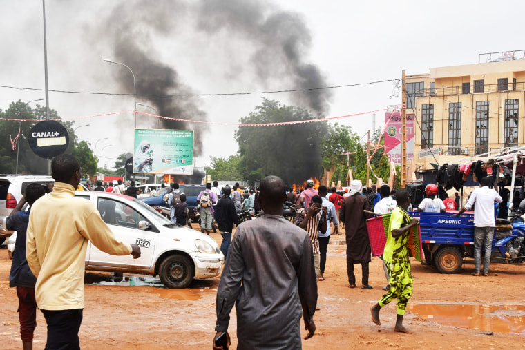 People crowd the street while supporters of the Nigerien defense and security forces attack the headquarters of the Nigerien Party for Democracy and Socialism