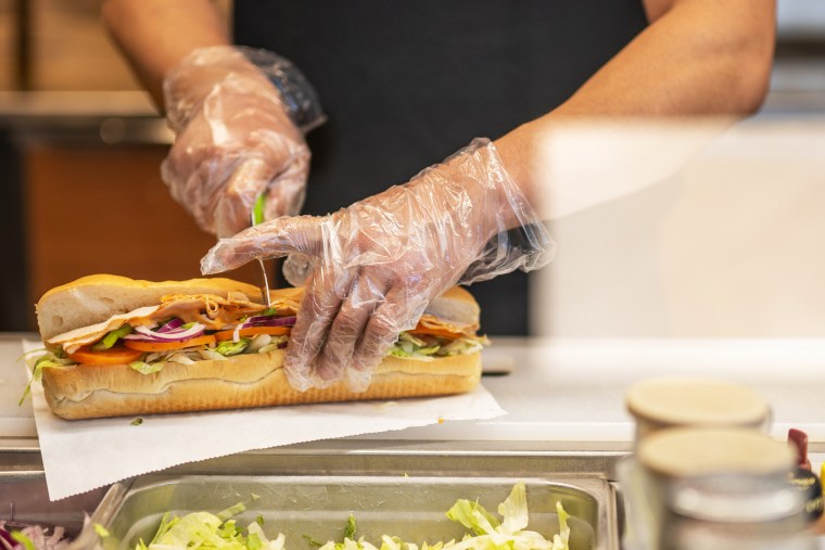 An employee cuts a Subway sandwich
