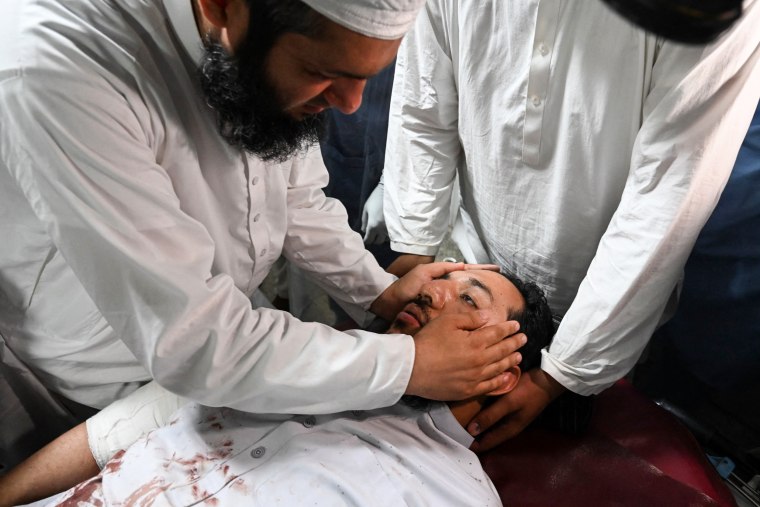 An injured man is comforted by a relative in a hospital in Peshawar, Pakistan, on July 30, 2023, after at least 55 people were killed and dozens more wounded by a suicide bombing at a political gathering of a leading Islamic party.