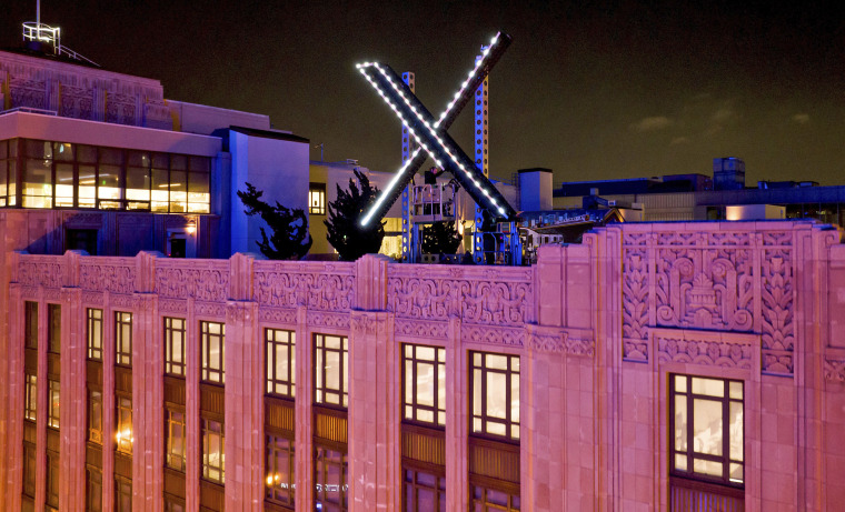 Workers install lighting on an "X" sign atop the company headquarters, formerly known as Twitter, in downtown San Francisco, on July 28, 2023.