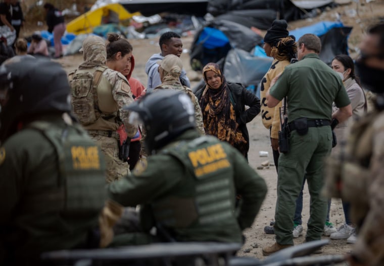Agentes de la Patrulla Fronteriza custodian a migrantes en la frontera entre Tijuana y San Diego, el 12 de mayo de 2023.

