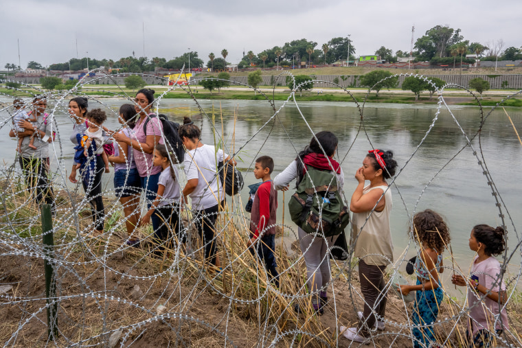 Personas que buscan asilo hablan con las fuerzas del orden después de cruzar el Río Grande hacia Estados Unidos el 14 de junio de 2023 en Eagle Pass, Texas.