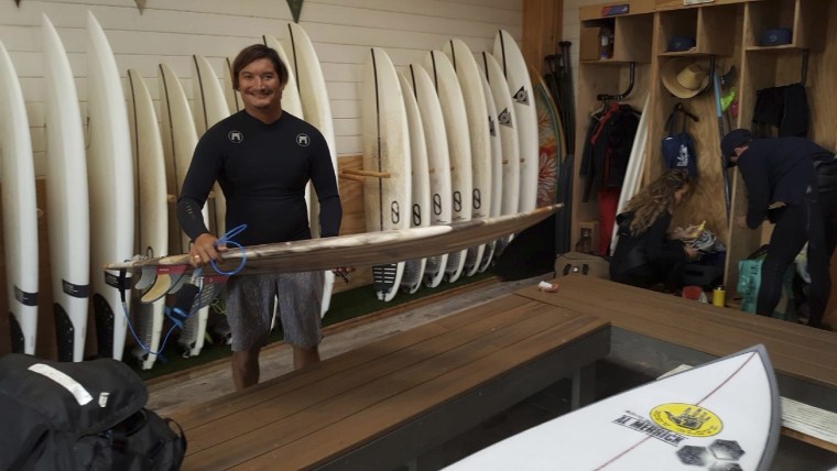 Mikala Jones on May 19, 2019, at Surf Ranch in Lemoore, California, holding a surfboard his brother made using material from the agave plant.
