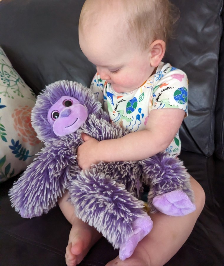 Charlie's daughter, Penelope, hugs the purple monkey his wife made.