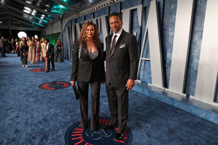 Tina Knowles-Lawson and Richard Lawson pose in black tuxedos on the blue carpet of the Vanity Fair party.