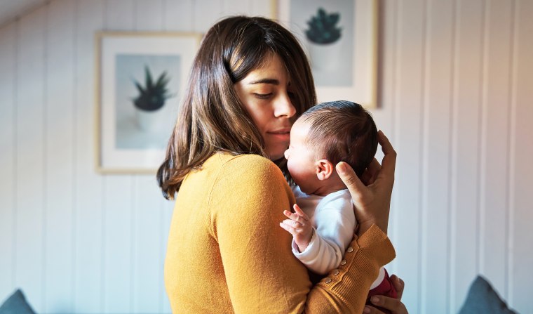 Side view of new mother comforting her newborn while crying. 