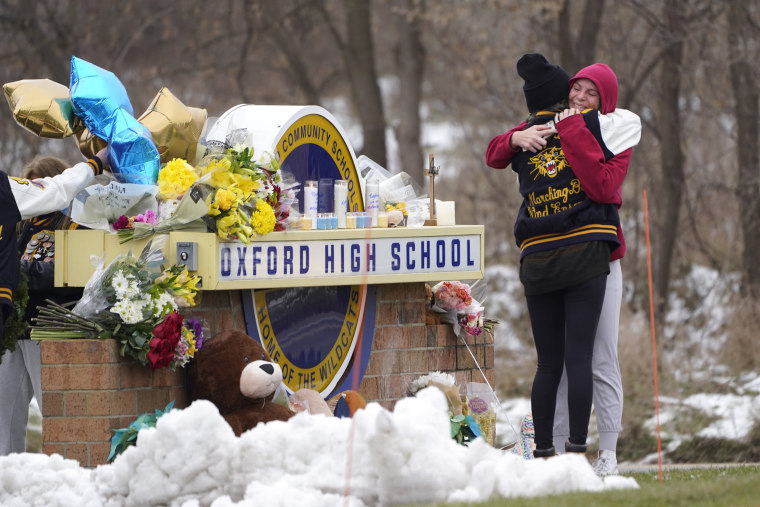 Students hug at a memorial on Dec. 1, 2021, following a shooting at Oxford High School in Oxford, Mich.