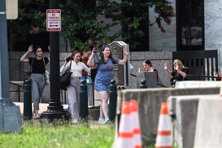 Image: People walk out of the Russell Senate Office Building with their hands in the air on Aug. 2, 2023, after unconfirmed reports of an active shooter in the building near the U.S. Capitol. 