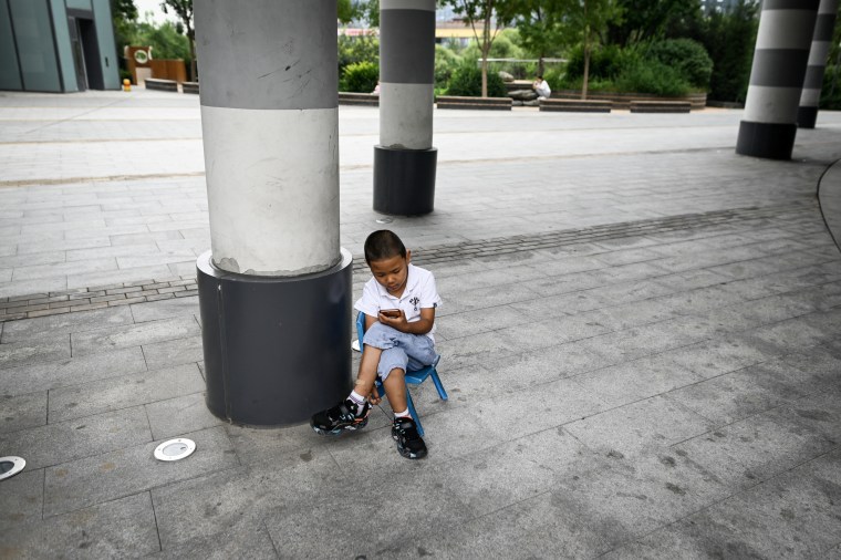A child uses a mobile phone outside a restaurant in Beijing on September 14, 2021.
