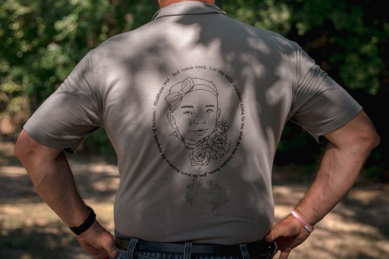 The back of a t-shirt worn by Autumn Wells' grandfather, Joel Wells, at the family burial plot. The shirt has a image of Autumn's face with a bible quote surrounding it.