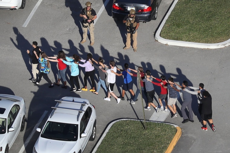 People are brought out of the Marjory Stoneman Douglas High School after a shooting n Parkland, Fla., 