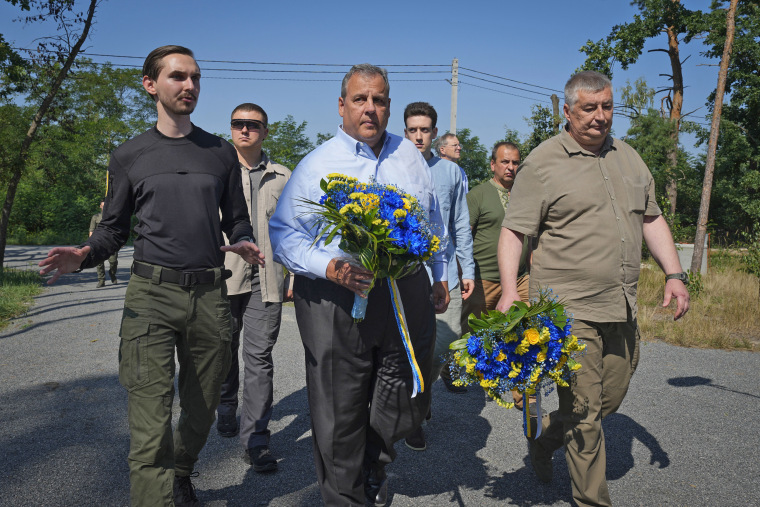 Former New Jersey Gov. Chris Christie, center, participates in a flower laying ceremony as he visits a former defense line in Moshchun, Ukraine, on the outskirts of Kyiv, Friday, Aug. 4, 2023. 