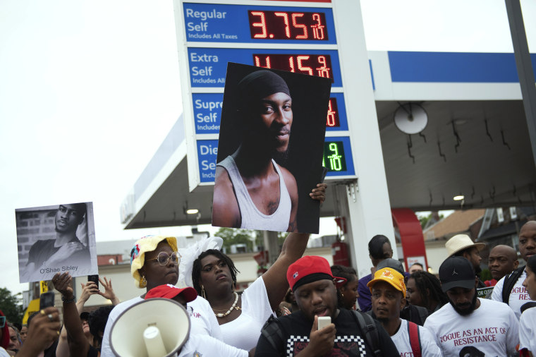 People gather at a gas station during a vigil to memorialize O'Shae Sibley