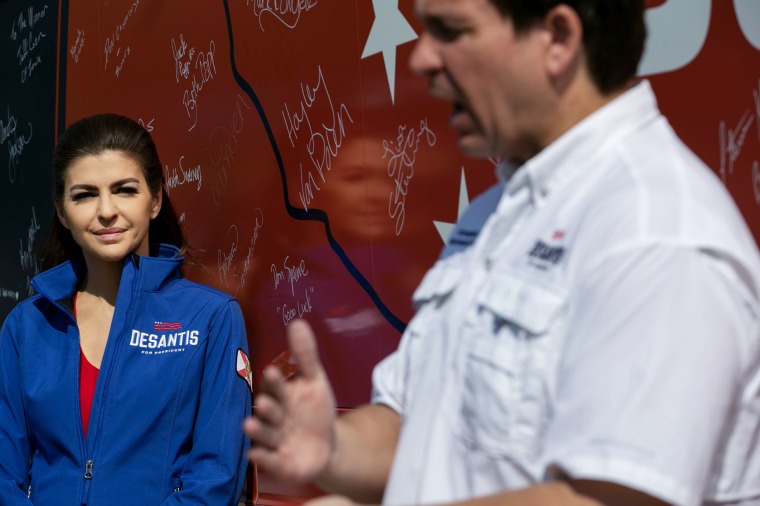 Casey DeSantis listens to her husband, Gov. Ron DeSantis of Florida, talk to reporters in Cedar Falls, Iowa, on Saturday. 