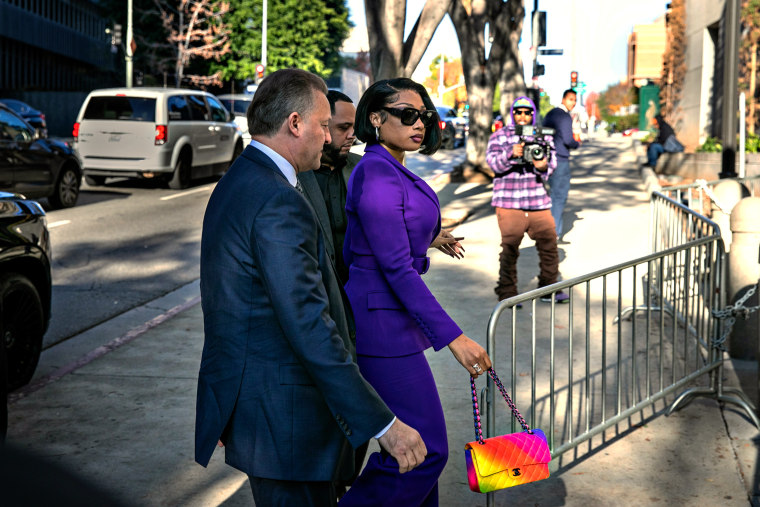 Megan Thee Stallion and two men in suits walks through barricades to enter court