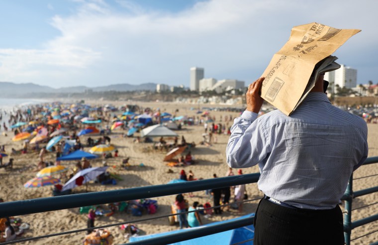 A person uses a piece of cardboard as a sun shade on the Santa Monica pier.
