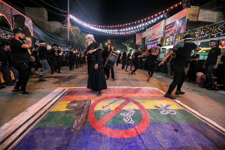 Shiite Muslim devotees self-flagellate over an unfurled banner on the ground depicting the Pride rainbow flag defaced with a boot and the Arabic slogan "no to homosexual society" ahead of the Shiite holy day of Ashoura in Nasiriyah, Iraq, on July 25, 2023. 