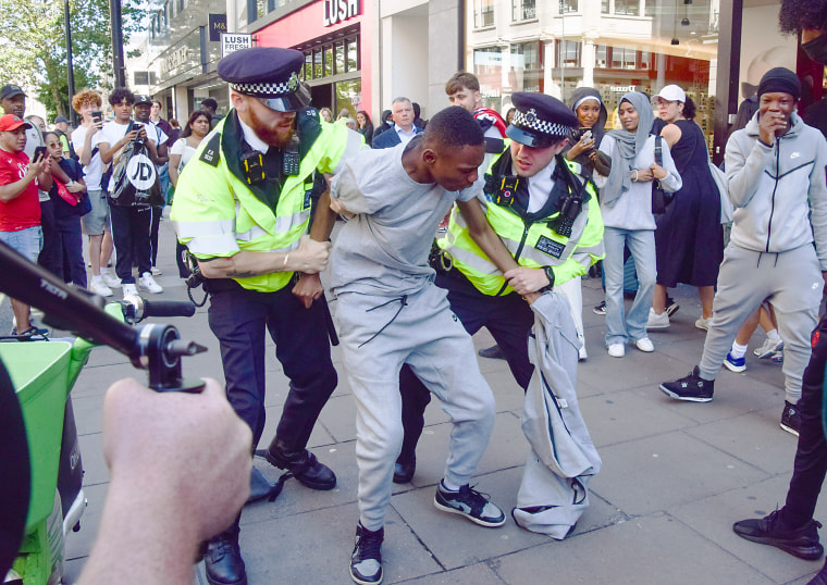 Police officers detain a young man on Oxford Street in London