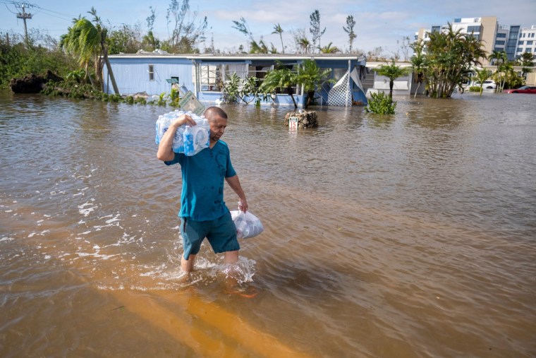 A man walks through a flooded neighborhood in the aftermath of Hurricane Ian in Fort Myers, Fla.