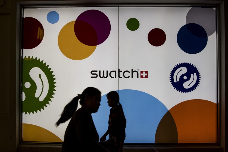 People  walk past an ad for Swatch in Macau, China