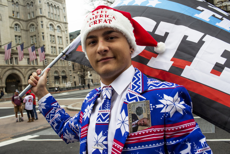 Wearing a red, white, and blue and winter-themed suit, Dylan Quattrucci waves a "Stop the Steal" flag during a rally