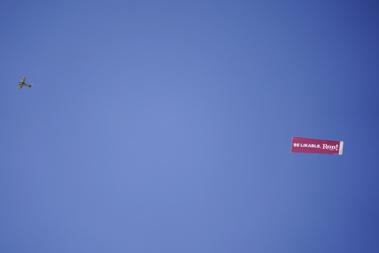 A plane flies over the Iowa State Fair pulling a banner with a goading message for Gov. Ron DeSantis