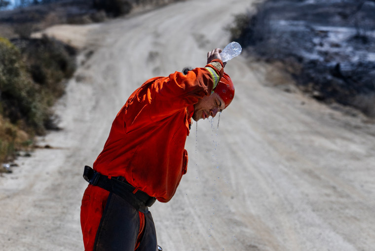 A member of the Prado fire crew tries to cool off in the  105 degree heat while putting out hotspots  at the Rabbit fire in Beaumont, Calif., on July 16, 2023.