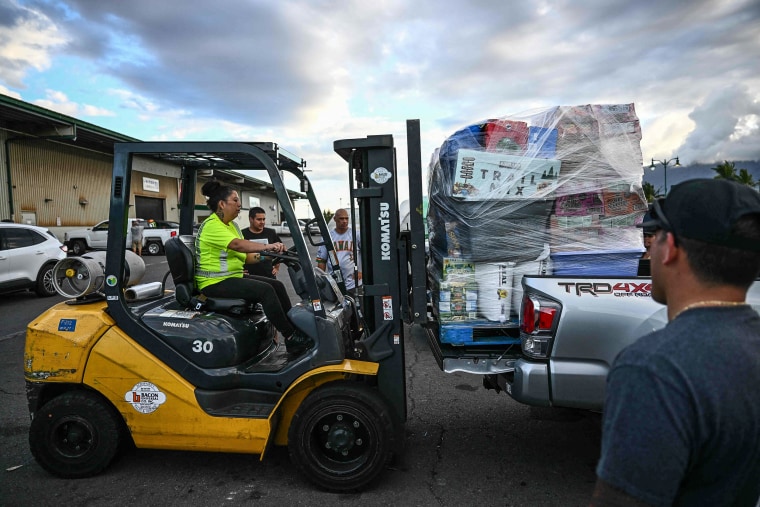 Image: A forklift loads a pallet of supplies and aid donations flown in from the Hawaiian island of Kauai into a pickup truck at the Kahului airport cargo terminal in the aftermath Maui wildfires in Kahului, Hawaii on Aug. 13, 2023. 