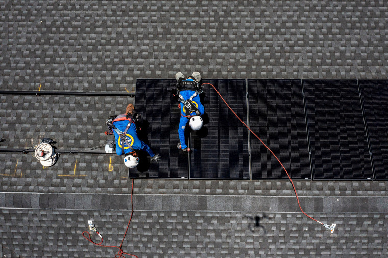 Workers install solar panels on a home in Napa, Calif., on July 17, 2023.