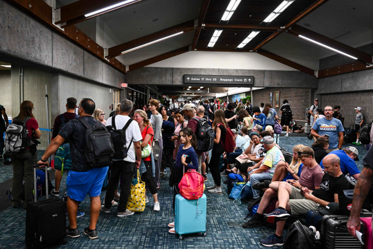 Passengers try to rest and sleep after canceled and delayed flights while others wait to board flights off the island as thousands of passengers were stranded at the Kahului Airport in Kahului, Hawaii, on Aug. 9, 2023.
