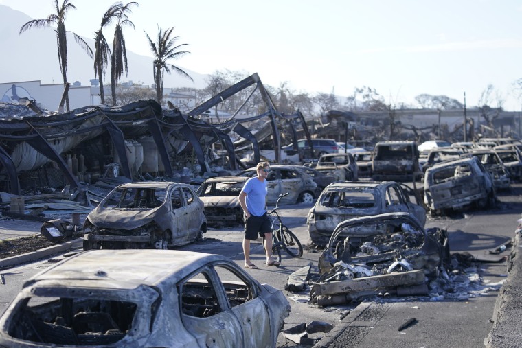 A man walks through wildfire wreckage in Lahaina, Hawaii